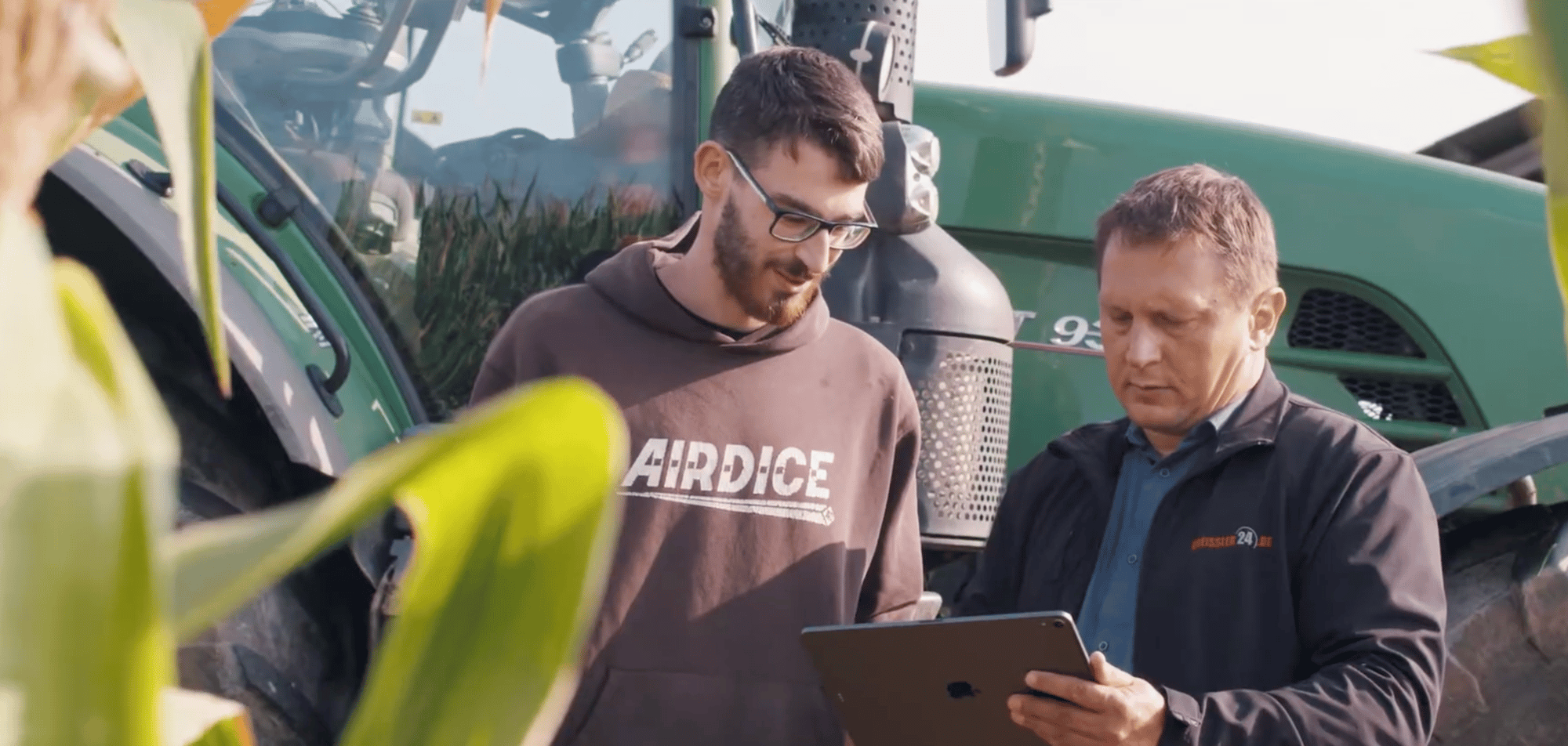 ein verkäufer und bauer stehen auf einem feld mit einem ipad in der hand